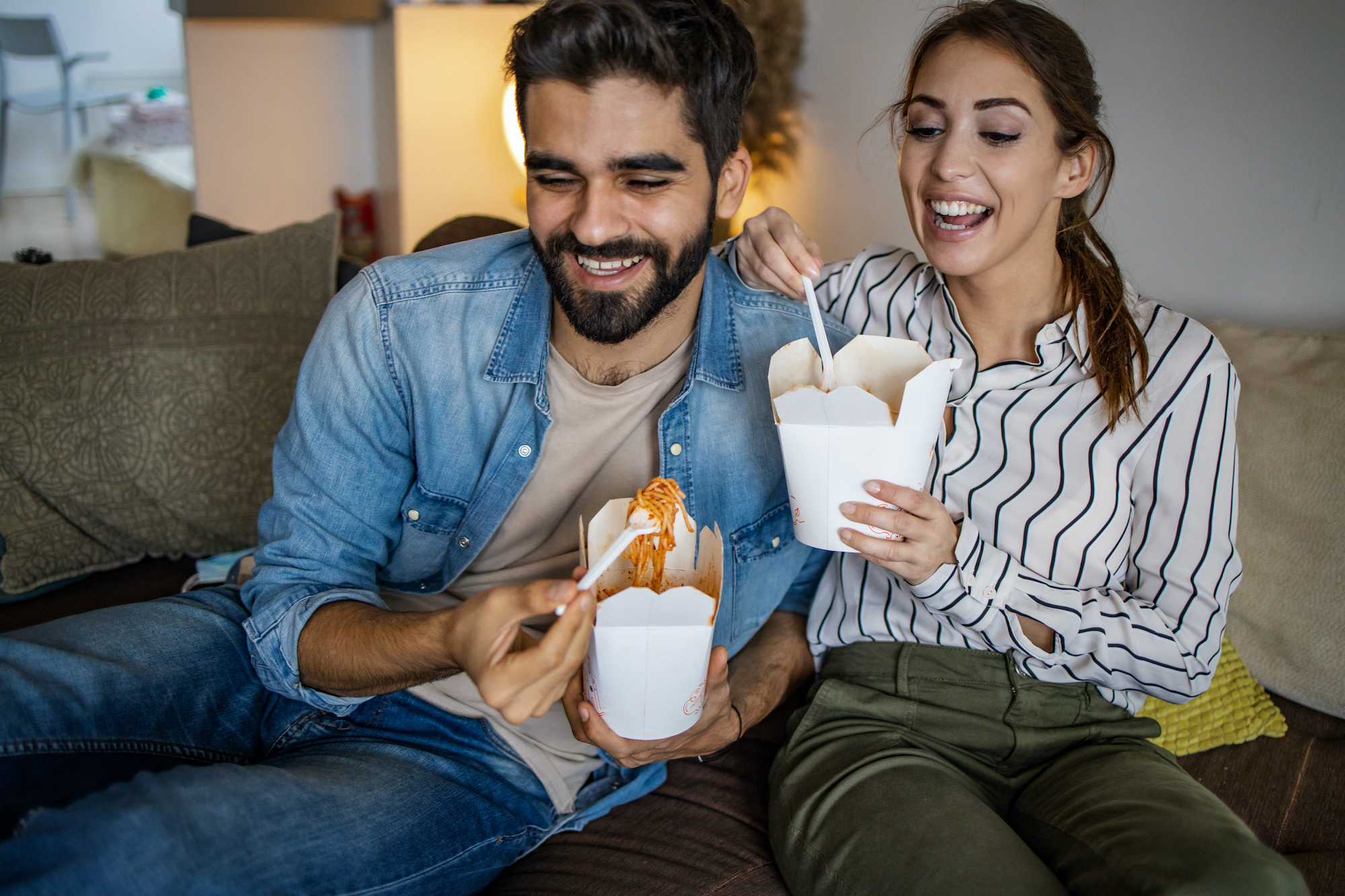 Home delivery. Couple relaxing at home and eating pasta