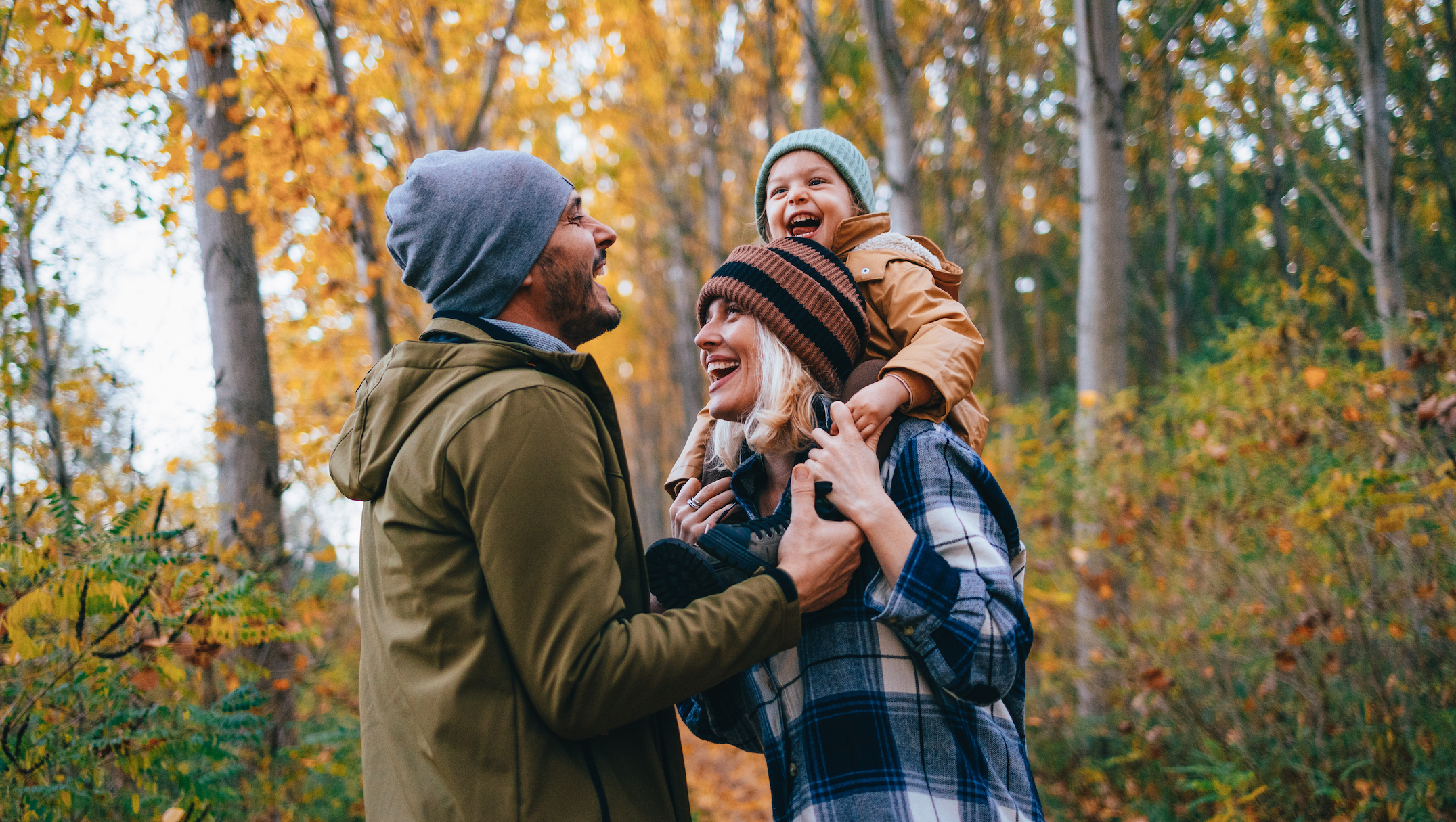 blog_header_five_signs_you_might_be_underinsured A family takes a walk in the fall woods with daughter on shoulders